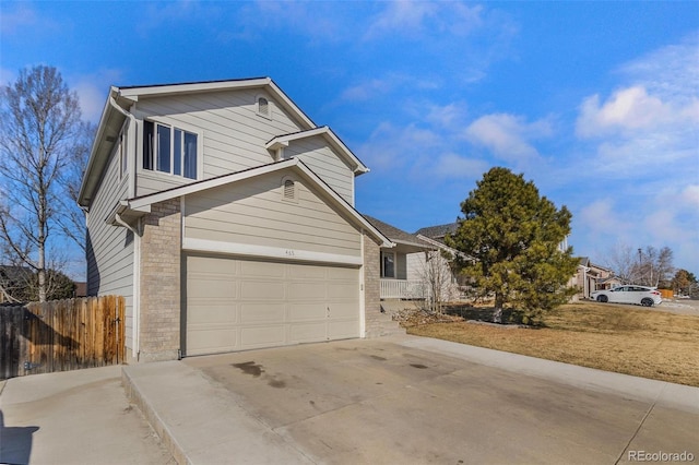 view of front of property with concrete driveway, fence, and brick siding