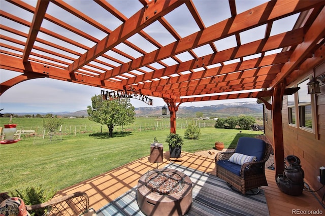 wooden deck featuring a pergola, an outdoor fire pit, and a lawn