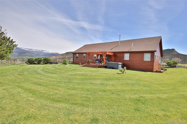 back of property featuring a deck with mountain view and a lawn