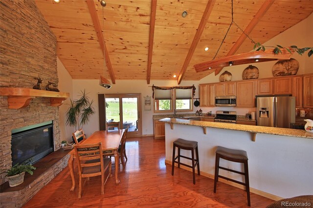 kitchen with light stone countertops, a fireplace, appliances with stainless steel finishes, hardwood / wood-style flooring, and wood ceiling