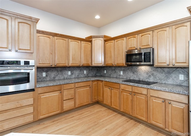 kitchen with decorative backsplash, stainless steel appliances, and light hardwood / wood-style floors