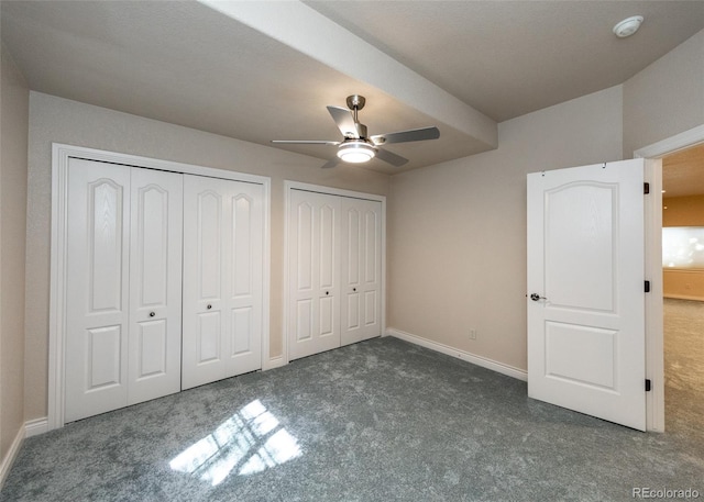 unfurnished bedroom with two closets, dark colored carpet, and ceiling fan