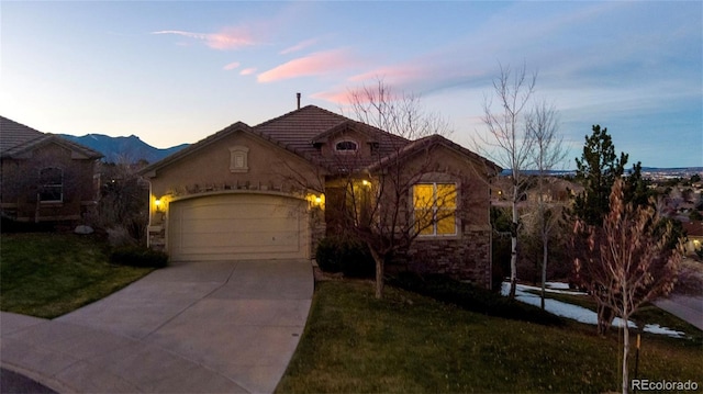 view of front of house with a mountain view, a garage, and a lawn