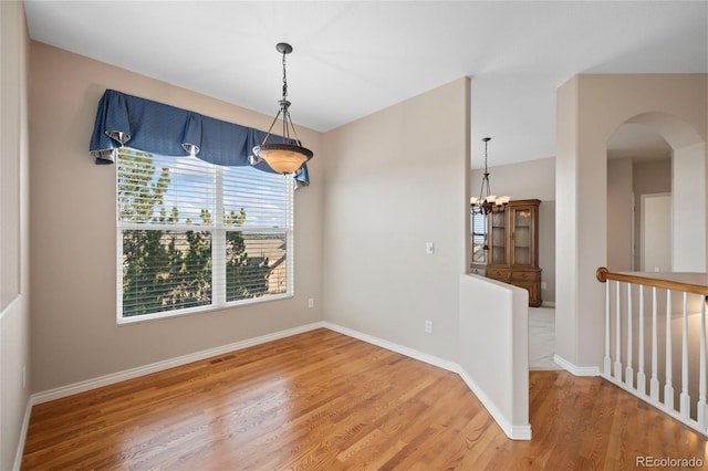 empty room with hardwood / wood-style flooring and a chandelier