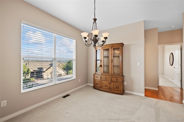 dining space with light colored carpet and an inviting chandelier