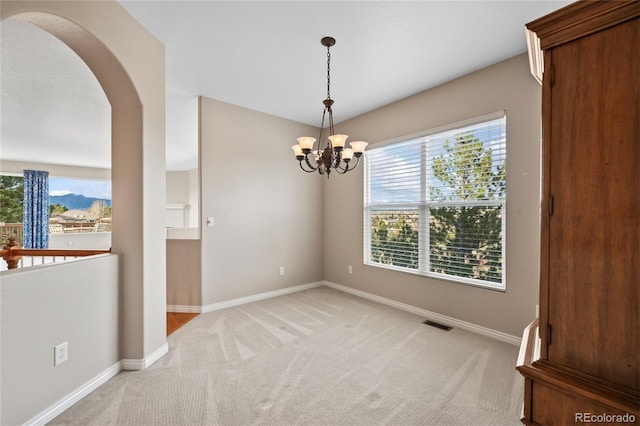 carpeted empty room with a notable chandelier