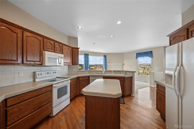 kitchen featuring decorative backsplash, light wood-type flooring, white appliances, sink, and a center island