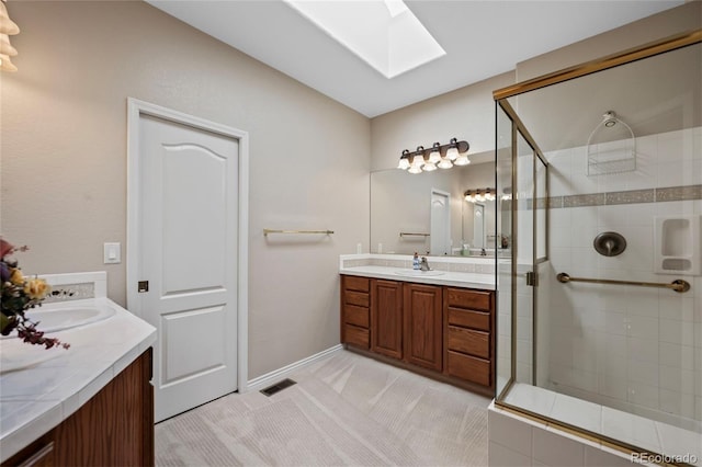 bathroom featuring vanity, a skylight, and a shower with door