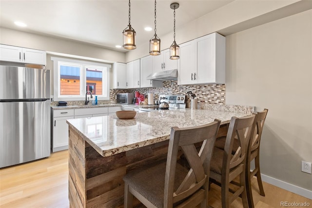 200 Primrose Path Unit 11, Breckenridge, CO 80424 - kitchen with stainless steel appliances, under cabinet range hood, a peninsula, a breakfast bar area, and tasteful backsplash