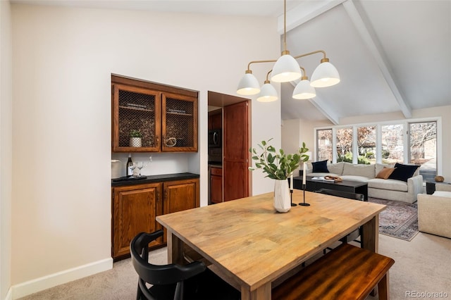 dining room featuring light carpet, lofted ceiling with beams, and a notable chandelier