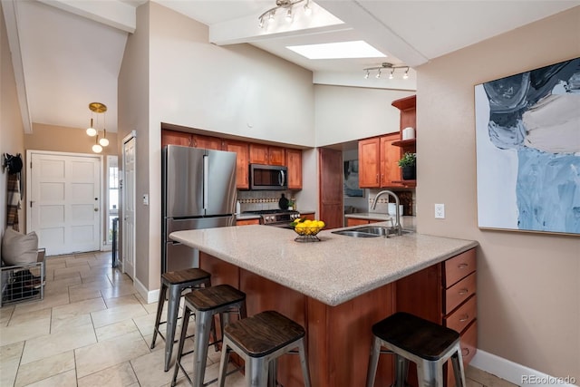 kitchen with appliances with stainless steel finishes, a skylight, tasteful backsplash, sink, and a breakfast bar area