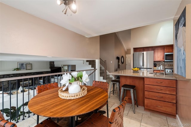 tiled dining room featuring vaulted ceiling and sink