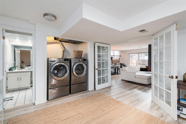 laundry room with light hardwood / wood-style flooring, independent washer and dryer, and french doors