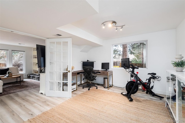 home office with french doors, plenty of natural light, and light hardwood / wood-style flooring