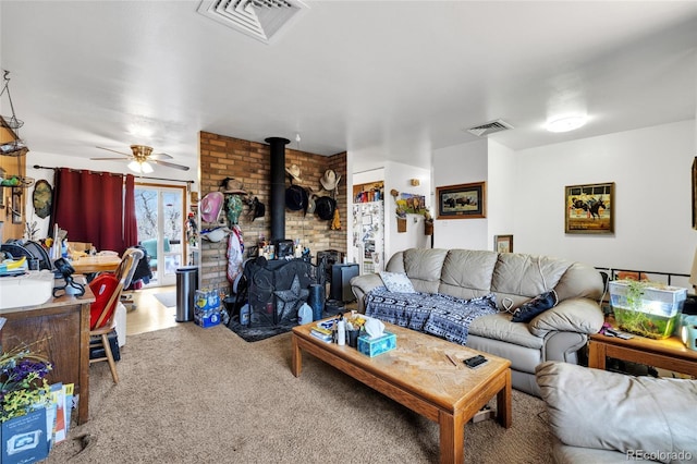 living room with a wood stove, ceiling fan, and carpet