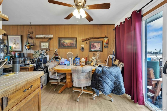 dining area with wooden walls and ceiling fan