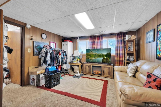 living room featuring carpet flooring, wood walls, and a drop ceiling