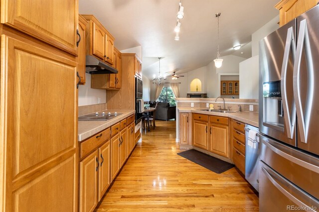 kitchen featuring hanging light fixtures, stainless steel refrigerator with ice dispenser, rail lighting, light wood-type flooring, and vaulted ceiling