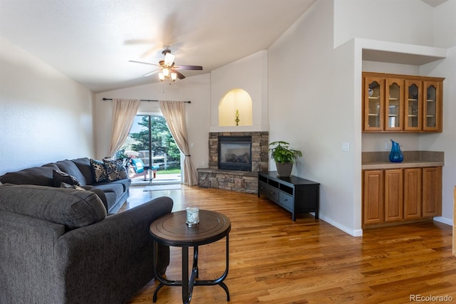 living room featuring light hardwood / wood-style floors, a fireplace, ceiling fan, and vaulted ceiling