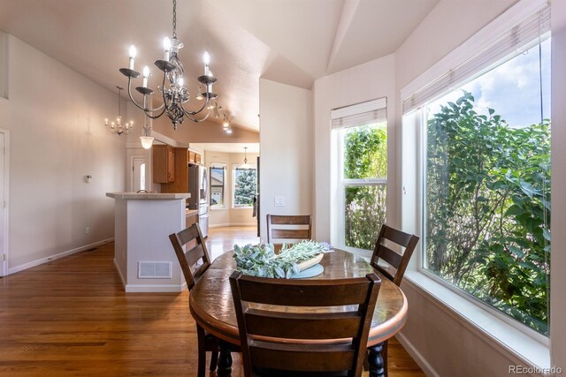 dining space with hardwood / wood-style floors, lofted ceiling, and a notable chandelier