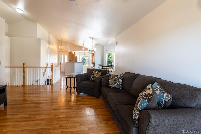 living room featuring an inviting chandelier, lofted ceiling, and hardwood / wood-style flooring