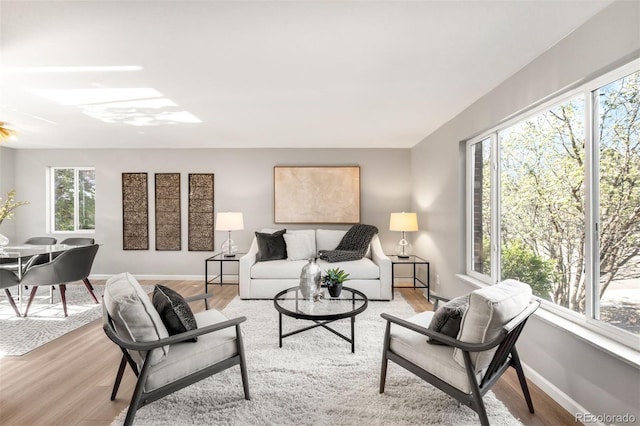living area with plenty of natural light, light wood-style floors, and a ceiling fan