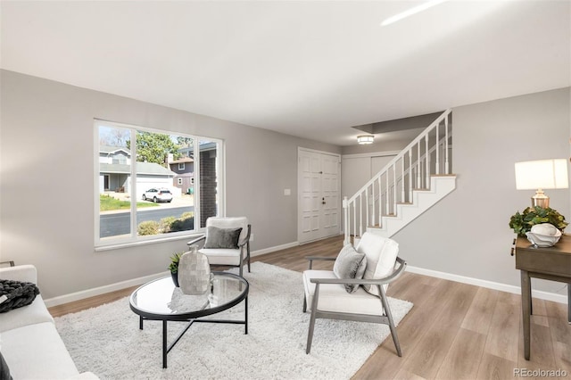 living area with stairway, light wood-style floors, and baseboards