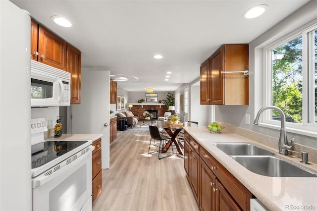 kitchen with white appliances, a sink, open floor plan, light countertops, and recessed lighting