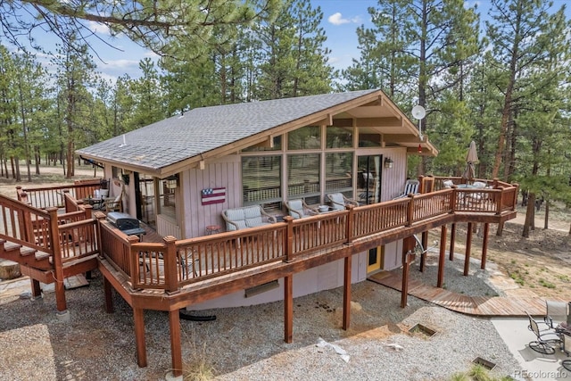 back of property with a deck and a shingled roof