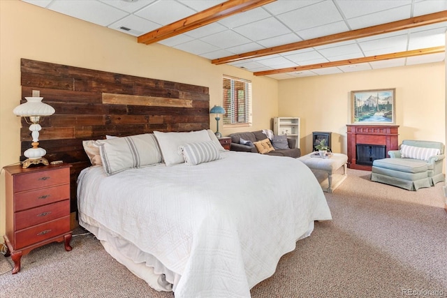 carpeted bedroom with a paneled ceiling and a glass covered fireplace