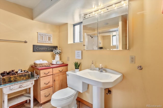 bathroom with toilet, a healthy amount of sunlight, and a shower with shower door