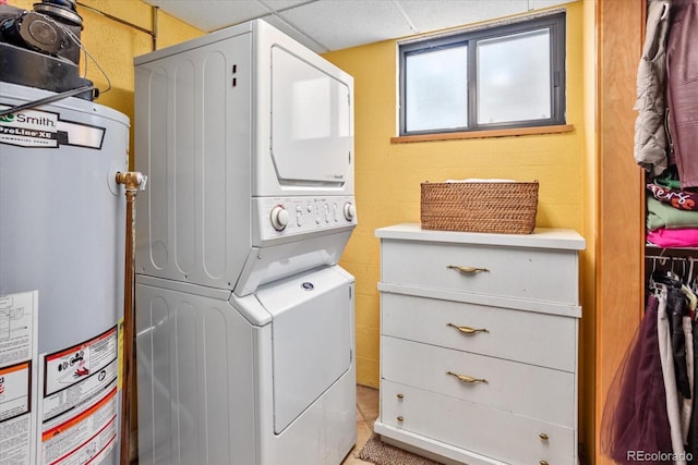 clothes washing area with laundry area, stacked washer and clothes dryer, and water heater