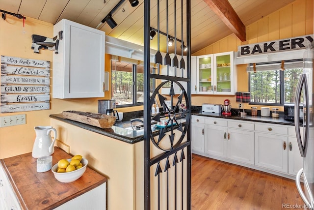 kitchen featuring light wood-style floors, a wealth of natural light, wooden ceiling, and vaulted ceiling with beams