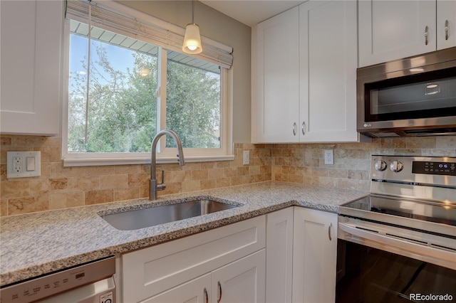 5925 W 86th Ave, Arvada, CO 80003 - kitchen with stainless steel appliances, white cabinetry, backsplash, light stone countertops, and hanging light fixtures