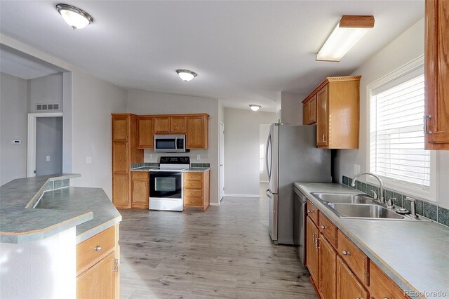 kitchen with sink, light wood-type flooring, stainless steel appliances, and vaulted ceiling