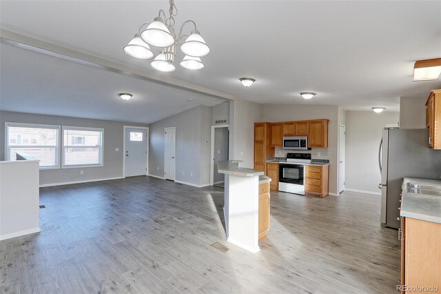 kitchen featuring hanging light fixtures, vaulted ceiling, light hardwood / wood-style floors, stainless steel appliances, and a chandelier