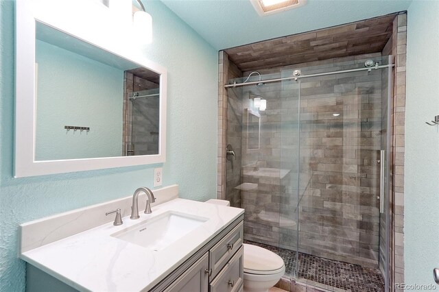 bathroom with vanity, toilet, and a shower with door