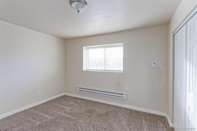 carpeted empty room with baseboard heating and a textured ceiling