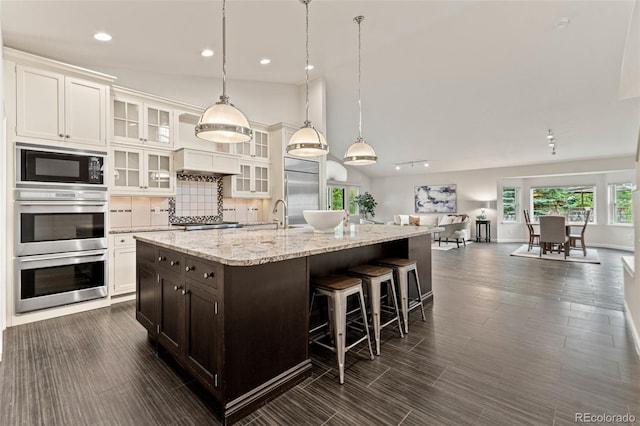 5980 Dunraven Ct, Golden, CO 80403 - kitchen with built in appliances, an island with sink, dark brown cabinets, white cabinets, and recessed lighting
