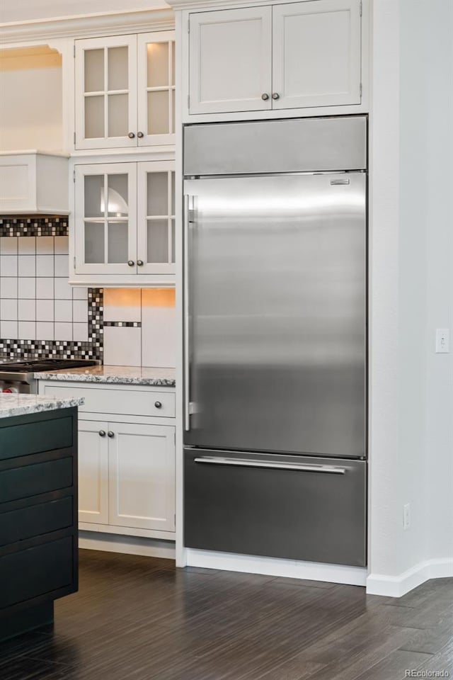 5980 Dunraven Ct, Golden, CO 80403 - kitchen with built in refrigerator, dark wood-type flooring, backsplash, glass insert cabinets, and light stone countertops