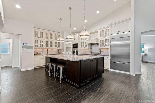 5980 Dunraven Ct, Golden, CO 80403 - kitchen with built in appliances, backsplash, an island with sink, white cabinetry, and recessed lighting