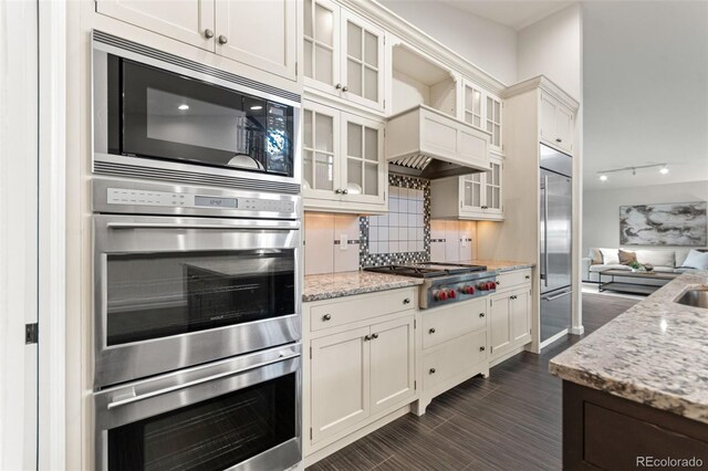 5980 Dunraven Ct, Golden, CO 80403 - kitchen with built in appliances, backsplash, light stone countertops, and white cabinets