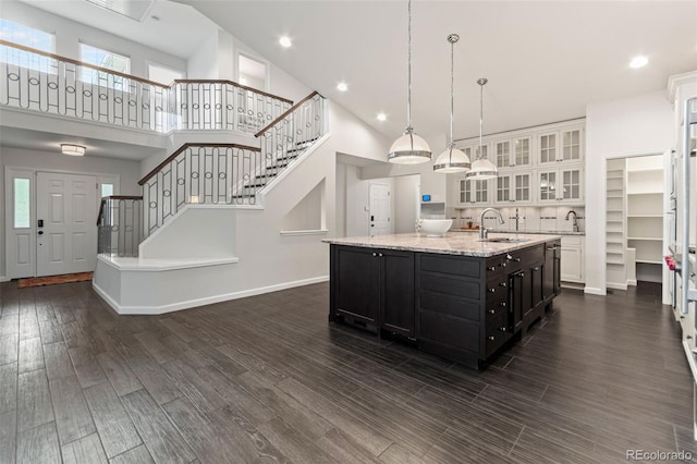 5980 Dunraven Ct, Golden, CO 80403 - kitchen with a center island with sink, a high ceiling, dark wood-type flooring, glass insert cabinets, and white cabinetry