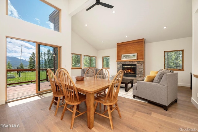452 Gcr 835, Fraser, CO 80442 - dining area with high vaulted ceiling, light wood-style floors, a stone fireplace, a ceiling fan, and healthy amount of natural light