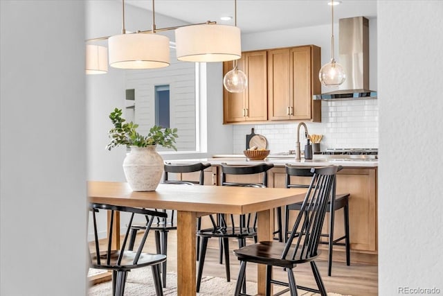 900 Eldorado Ln, Louisville, CO 80027 - kitchen featuring wall chimney range hood, decorative backsplash, light wood-style floors, decorative light fixtures, and light countertops