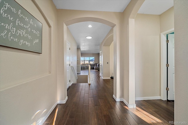 hallway with arched walkways, recessed lighting, baseboards, and wood finished floors