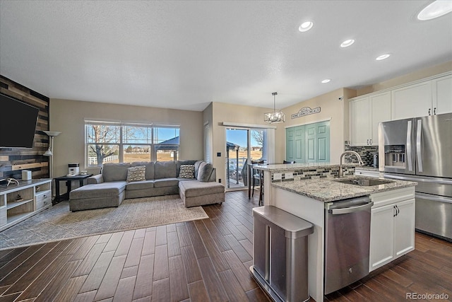 kitchen with a center island with sink, decorative backsplash, open floor plan, stainless steel appliances, and a sink