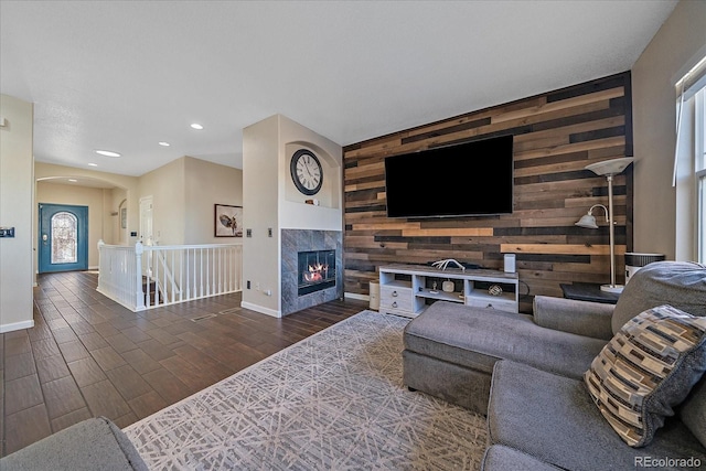 living area with recessed lighting, a premium fireplace, an accent wall, wooden walls, and wood finished floors