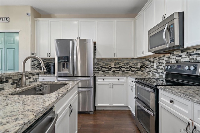 kitchen featuring dark wood-style floors, stainless steel appliances, backsplash, white cabinetry, and a sink