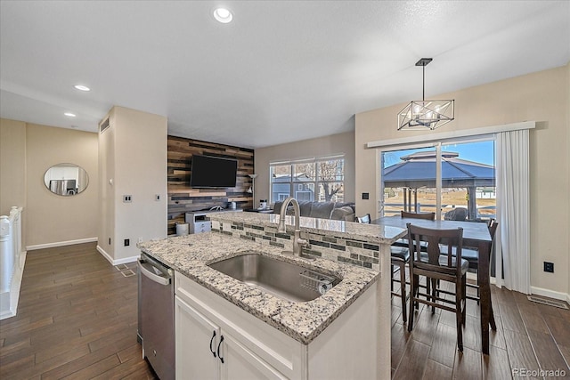 kitchen with a sink, white cabinetry, dark wood-style floors, open floor plan, and dishwasher